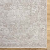 Close-up of a beige Tanko Washable Wool Area Rug with a traditional, distressed pattern on a wood floor. Swatch