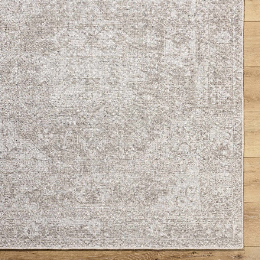 Close-up of a beige Tanko Washable Wool Area Rug with a traditional, distressed pattern on a wood floor. Swatch
