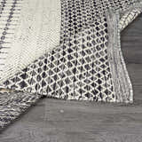 Close-up of the hand woven Tideswell Scandi Boho Wool Carpet with beige and black geometric patterns and fringe. Fold