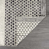 Close-up of the Tideswell Scandi Boho Wool Carpet. Features a geometric black and beige pattern and hand woven texture. Fold