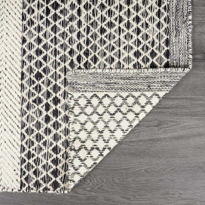 Close-up of the Tideswell Scandi Boho Wool Carpet. Features a geometric black and beige pattern and hand woven texture. Fold