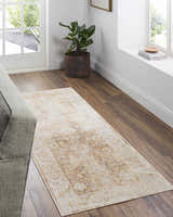 Entryway with a neutral sofa and the tan Aniyah Washable Area Rug on wood floors. Plant and books add warmth. Roomscene-Runner