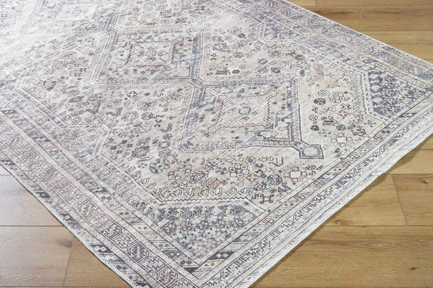 Close-up of the Trula Washable Area Rug Vivir x Livabliss. Beige and light gray traditional pattern. Machine woven polyester rug. Corner