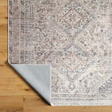 Close-up of Trula Washable Area Rug Vivir x Livabliss. Beige and light gray traditional pattern, machine woven. Fold