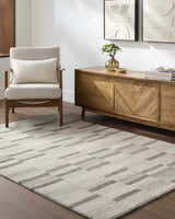 Living room scene with a light silver Timmy Area Rug, modern wood cabinet, and accent chair. Roomscene-Rectangle