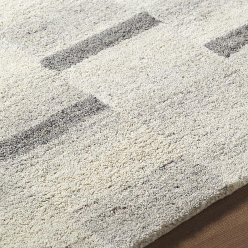 Close-up of the hand-tufted Timmy Area Rug. Light silver wool rug with a contemporary slate blue and sage block pattern. Texture