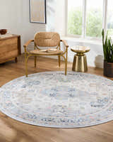 Living room scene with round Tana Washable Area Rug in Arctic Stone, woven chair, wood dresser, and gold side table. Roomscene-Round