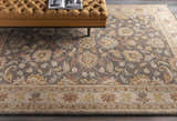 Living room scene with a tufted ottoman on the Cherryfield Hand Tufted Taupe Wool Rug. Floral pattern in taupe, beige, and yellow. Roomscene-Rectangle