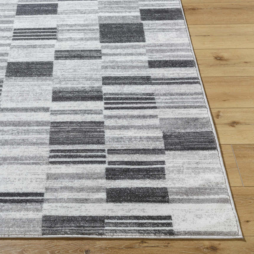 Close-up of the Tehya Gray Area Rug. Contemporary design with charcoal, gray, and light silver blocks and stripes. Front