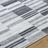 Close-up of the Tehya Gray Area Rug showing its charcoal, silver, and light gray geometric pattern and soft texture. Texture