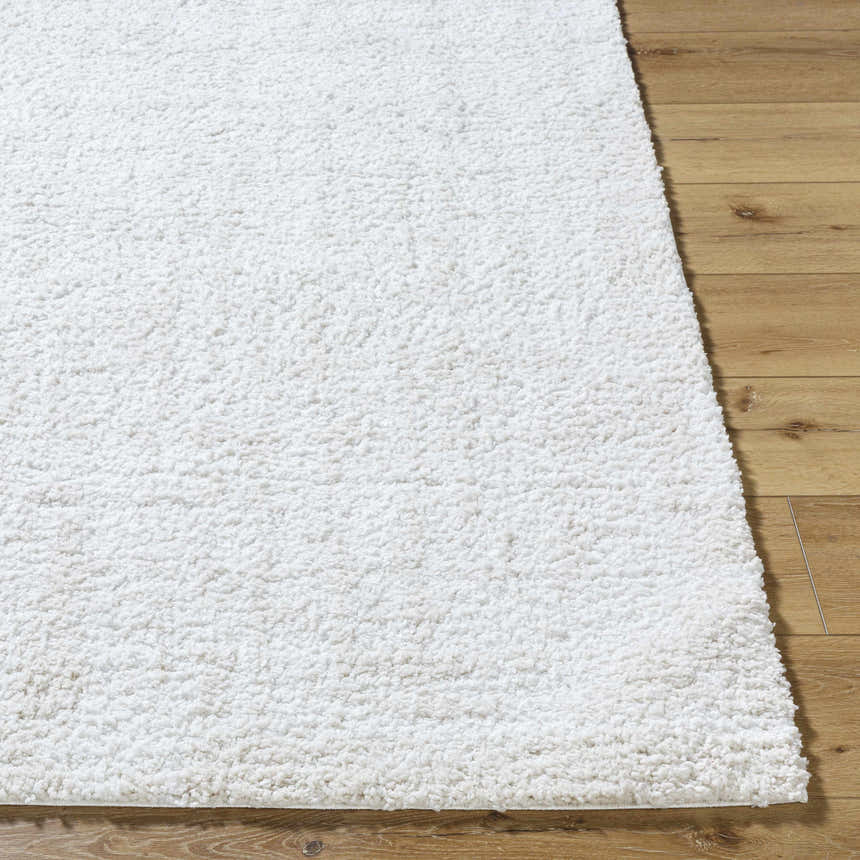 Close up of the white, shag Troya Area Rug showing texture and pile height on wood floor. Front