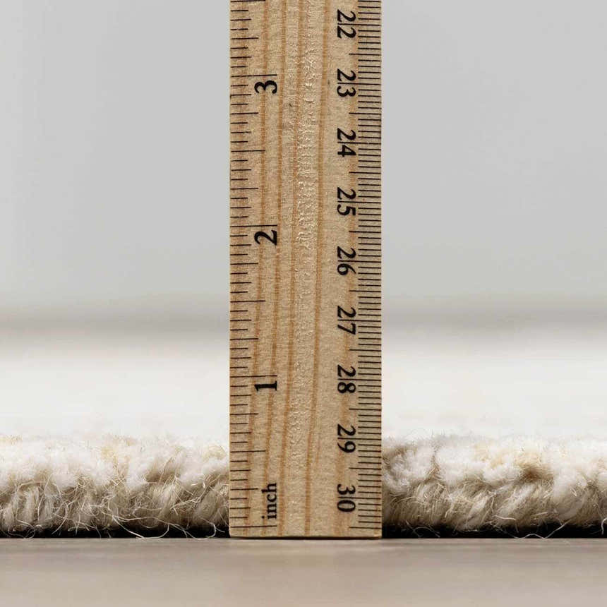 Close-up of the Teige Light Silver Area Rug showing its thick, hand-tufted wool pile height with a ruler. Pile