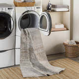 Laundry room scene with Tupsan Washable Area Rug coming out of dryer, jute rug underneath, neutral tones. Washing-Machine