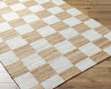 Close-up of Kamey Handmade Becki Owens x LIVABLISS rug. Jute rug with a light brown and white checkerboard pattern. Corner