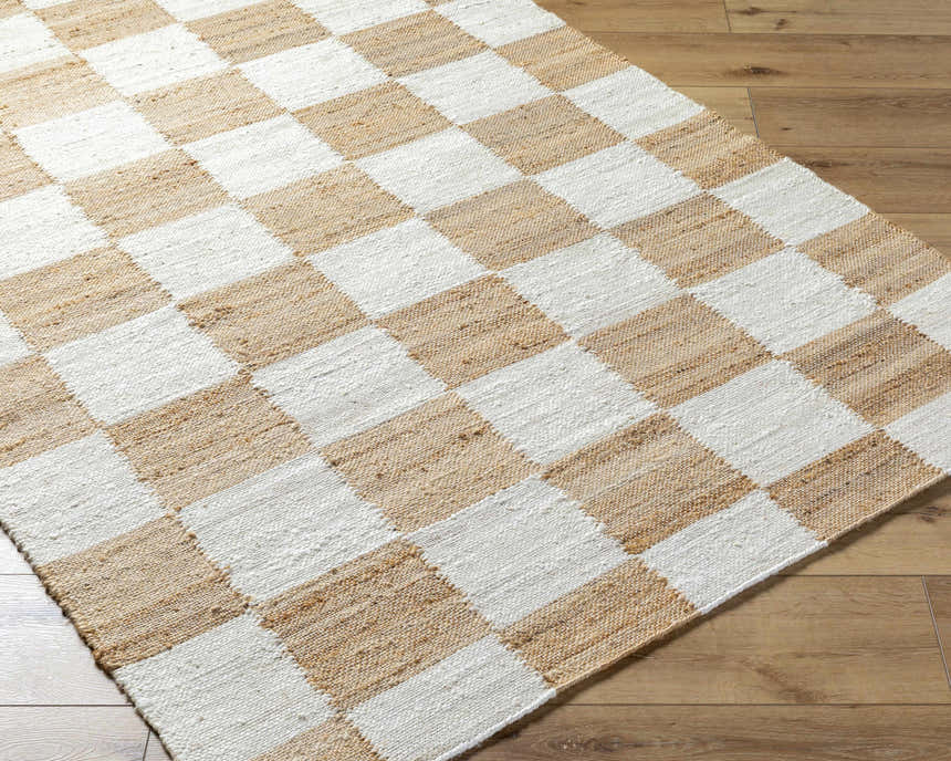 Close-up of Kamey Handmade Becki Owens x LIVABLISS rug. Jute rug with a light brown and white checkerboard pattern. Corner