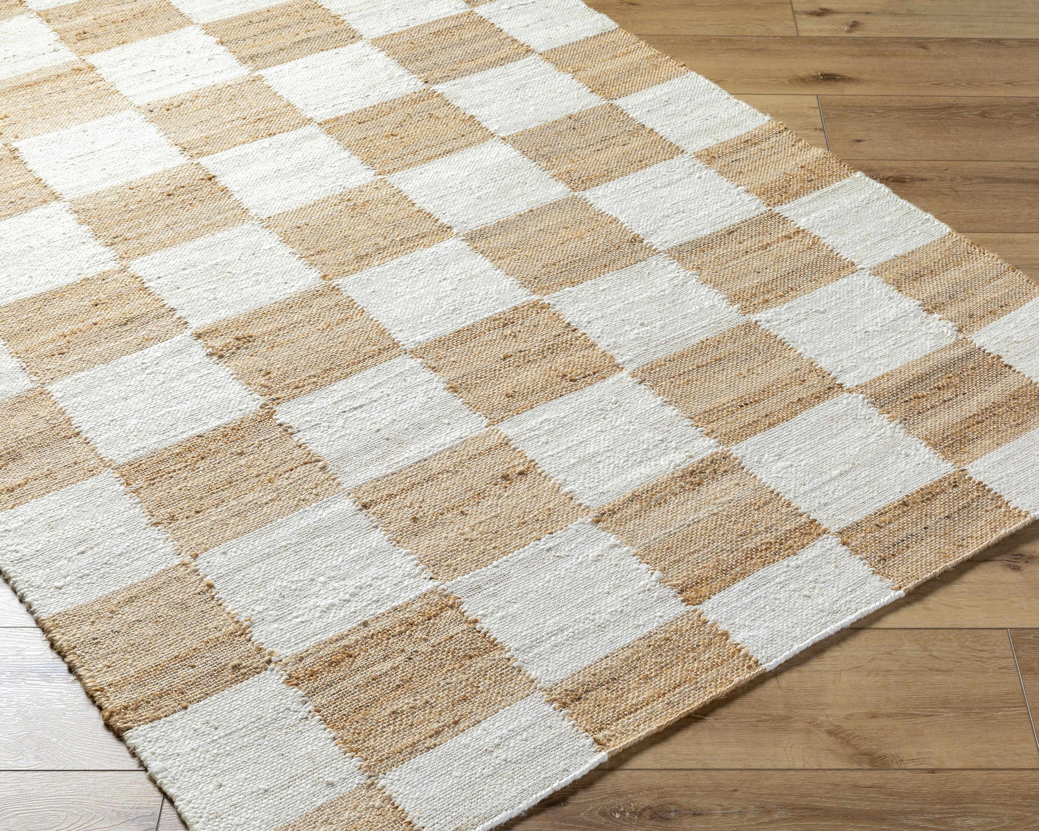 Close-up of Kamey Handmade Becki Owens x LIVABLISS rug. Jute rug with a light brown and white checkerboard pattern. Corner