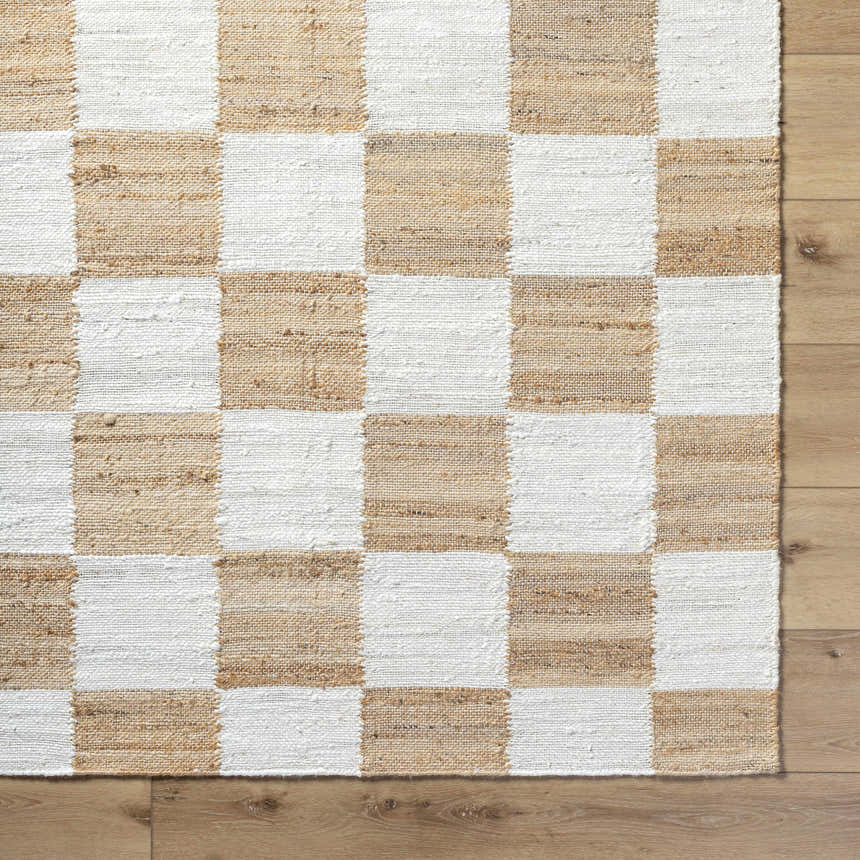 Close-up of Kamey Handmade Becki Owens x LIVABLISS rug. Jute rug with a checkerboard pattern in light brown and white. Corner