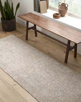 Hallway scene with a cream and sage Avalyn Area Rug under a wooden bench by a window. Roomscene-Runner