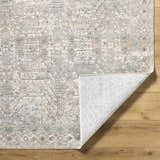 Close-up of the Avalyn Area Rug showing its cream, light sage, and slate traditional pattern and polyester texture. Fold