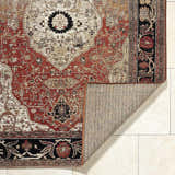Close-up of the Vonda Area Rug showing its traditional crimson, ivory, and charcoal floral pattern and machine-woven texture. Fold