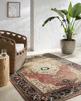 Light room scene with a crimson and ivory Vonda Area Rug, wicker chair, wood side table, and potted plant. Roomscene-Rectangle