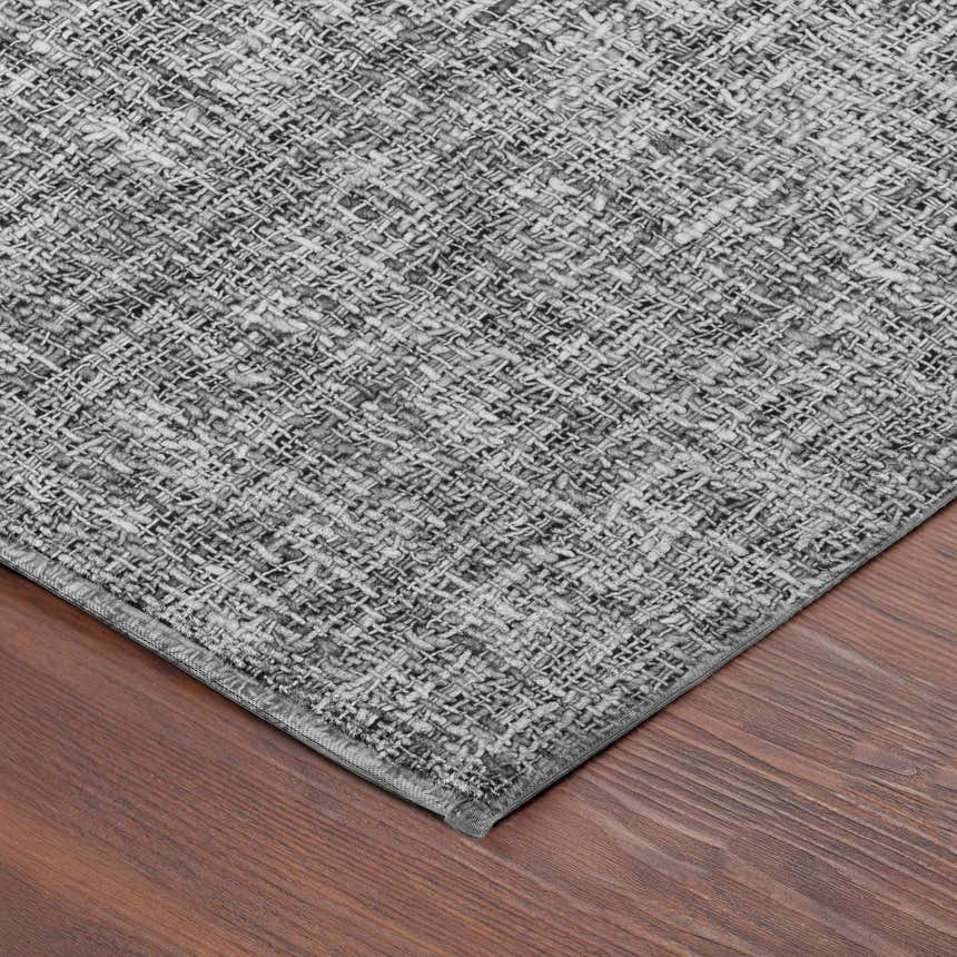 Close-up of the woven texture of the Dalyn Luxury Voyage VY1 Gray Washable Area Rug on a hardwood floor.
