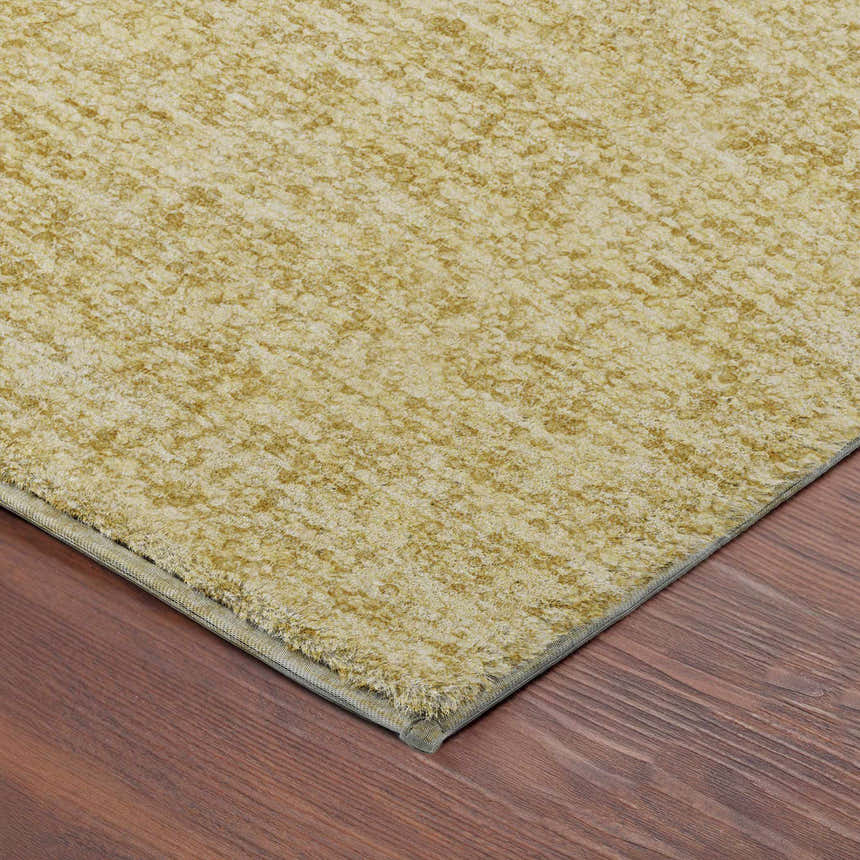Close-up of the textured Dalyn Luxury Voyage VY2 Wheat Washable Area Rug on dark wood floor. Peach tones.