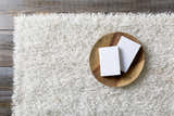Close-up of Browder Solid Beige Shag Area Rug showing its plush texture and color. Books on a wood plate sit on the rug. Styleshot