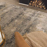 Living room scene with a neutral Whyalla Misty Thick Luxe Rug, tan chair, and fireplace with wood. Styleshot