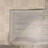 Close-up of the hand-woven Wolseth Area Rug showing the ivory textured pattern and gray backing on a wood floor. Fold