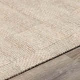 Close-up of the hand woven Wolseth Area Rug in off white and gray, showing texture and detail on wood floor. Pile
