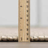 Close-up of the Wolseth Area Rug showing the pile height with a ruler. Off white wool and polyester texture. Pile