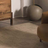 Close-up of the Wolseth Area Rug showing its textured, woven design in neutral tones, styled with wood furniture. Styleshot
