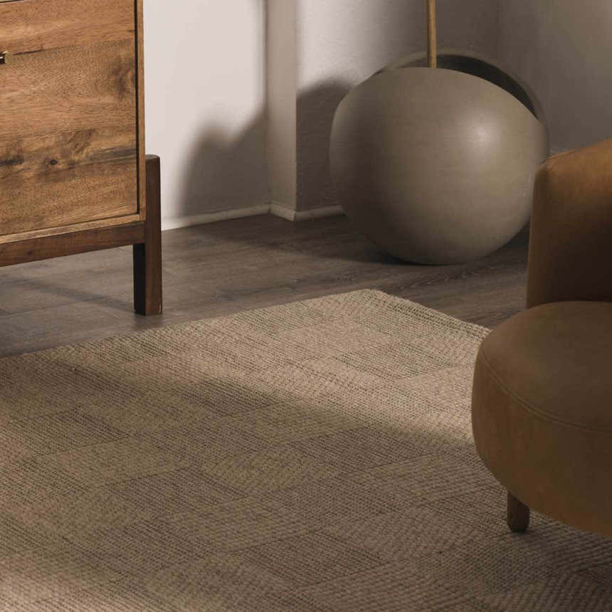 Close-up of the Wolseth Area Rug showing its textured, woven design in neutral tones, styled with wood furniture. Styleshot