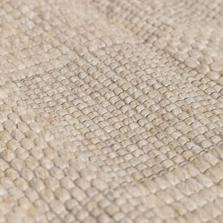 Close-up of the hand-woven Wolseth Area Rug, showing its textured ivory wool and polyester blend. Texture