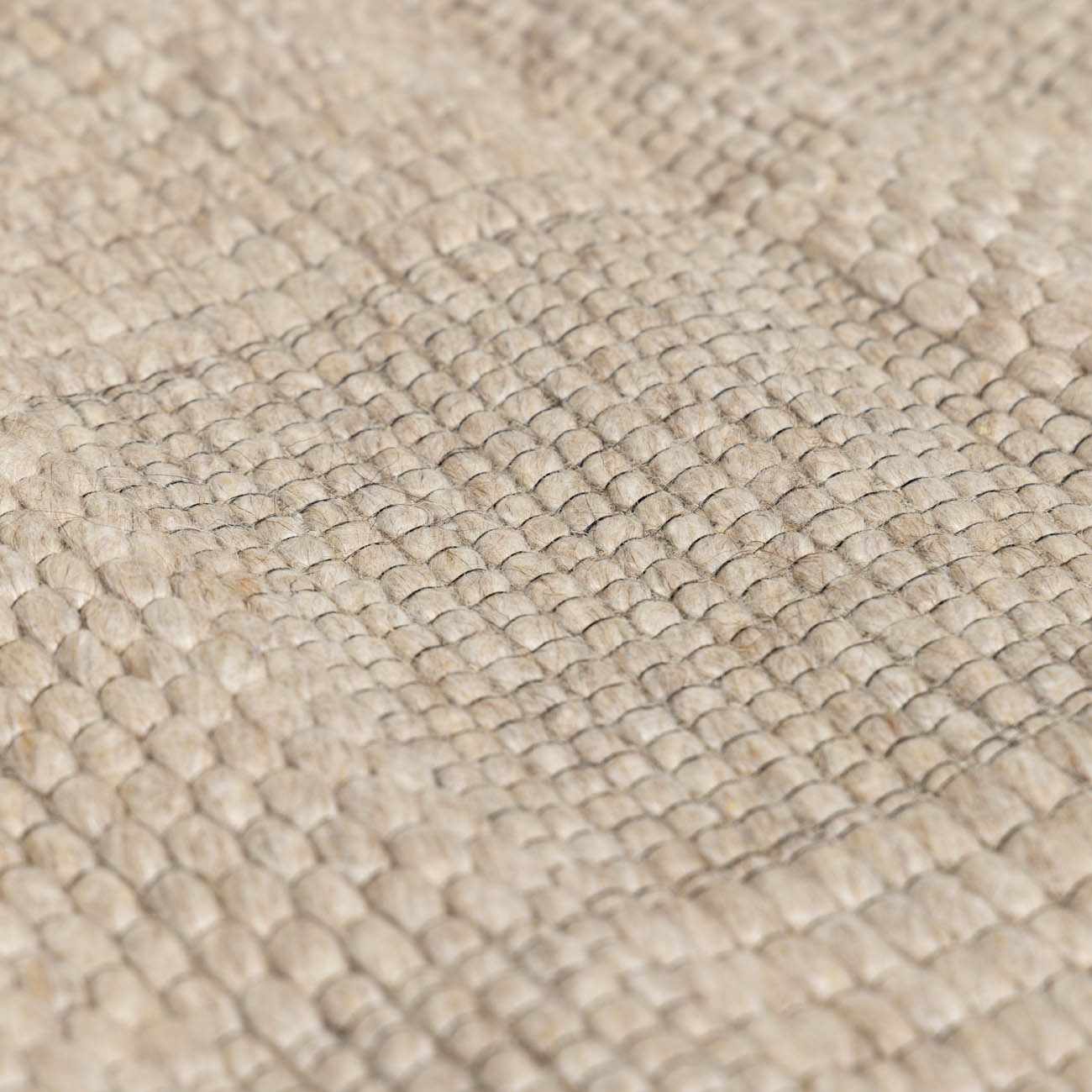Close-up of the hand-woven Wolseth Area Rug, showing its textured ivory wool and polyester blend. Texture