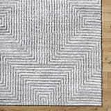 Close-up of the light silver Aerith Shag Area Rug, featuring a geometric pattern and soft, plush texture. Swatch