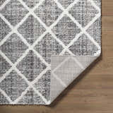 Close-up of the Anuhea Light Gray Area Rug showing diamond trellis pattern and soft texture on wood floor. Fold