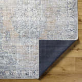 Close-up of the Yachi Washable Area Rug showing its farmhouse style, traditional pattern, and gray, silver, and prairie dust colors. Fold