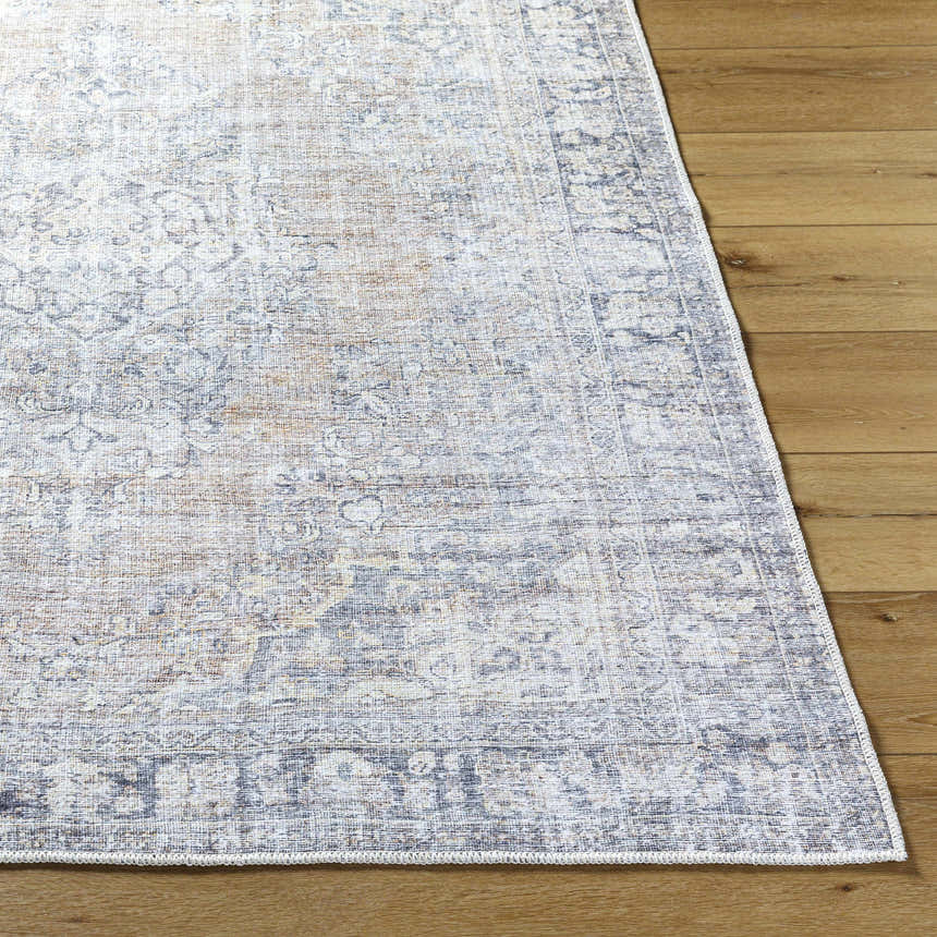 Close up of a gray and prairie dust Yachi Washable Area Rug on a wood floor, showing the traditional pattern and woven texture. Front