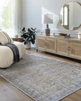 Living room scene with a gray Yachi Washable Area Rug, cream sofa, wood cabinet, round gold mirror, and hardwood floors. Roomscene-Rectangle