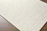 Close up of the Yadid Cream Wool Area Rug showing its subtle traditional pattern and soft, textured wool. Corner