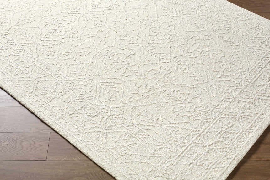 Close up of the Yadid Cream Wool Area Rug showing its subtle traditional pattern and soft, textured wool. Corner