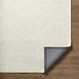 Close-up of the Yadid Cream Wool Area Rug showing its subtle floral pattern and hand-tufted texture on a wood floor. Fold