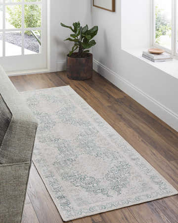 Entryway with Yanis Vintage Flat Pile Washable Rug in cream and green, wood floors, gray couch, and natural light. Roomscene-Runner