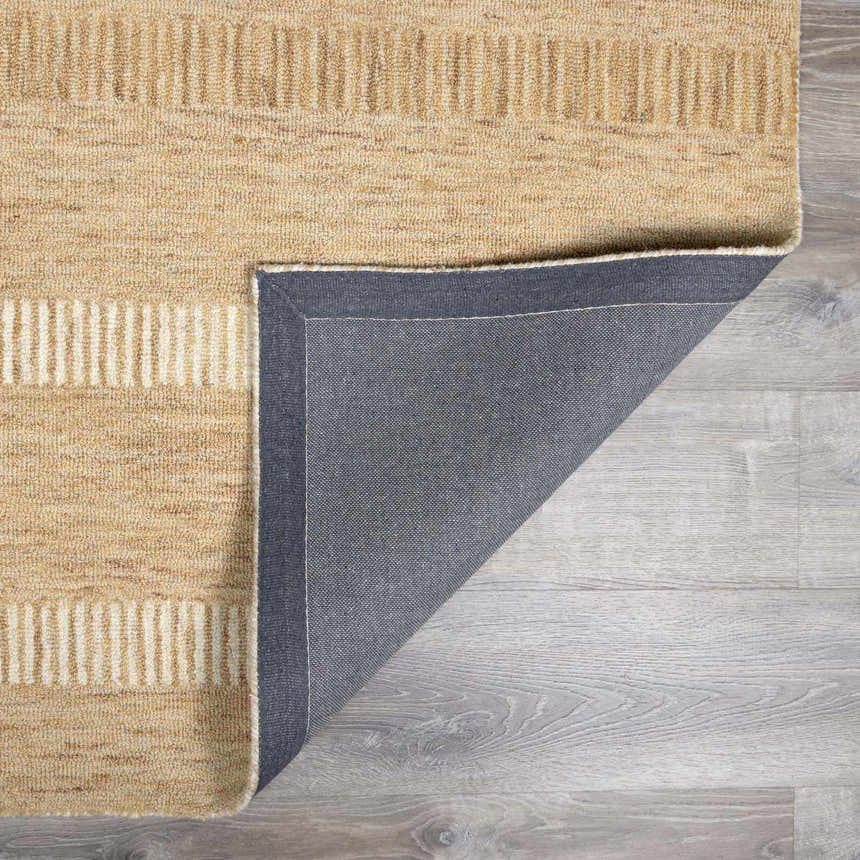 Close-up of the hand-tufted Yoyko Area Rug. Tan and pearl wool rug with a geometric stripe design. Fold