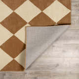 Close up of the Aradia Tan Area Rug showing a tan and cream diamond pattern and the rug backing. Fold