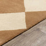 Close-up of the hand-tufted Aradia Tan Area Rug. Tan and cream wool squares on gray wood flooring. Contemporary style. Pile