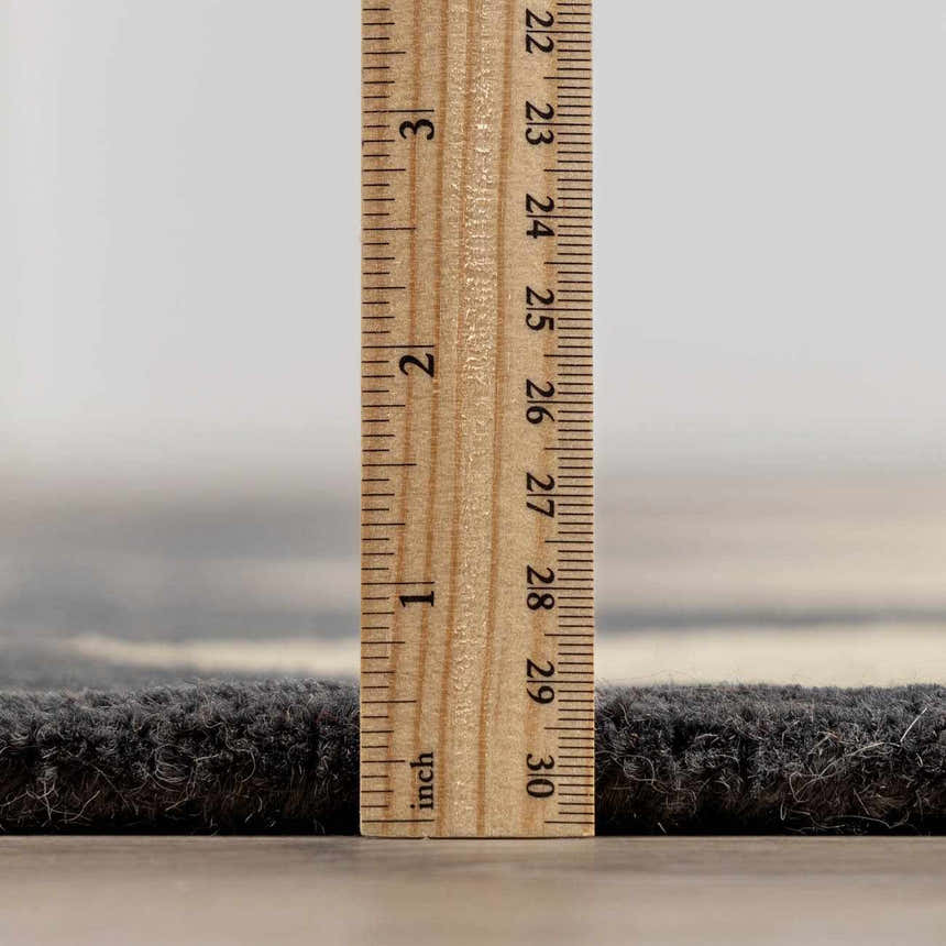Close-up of the Aradia Charcoal Area Rug showing its pile height with a ruler. Pile