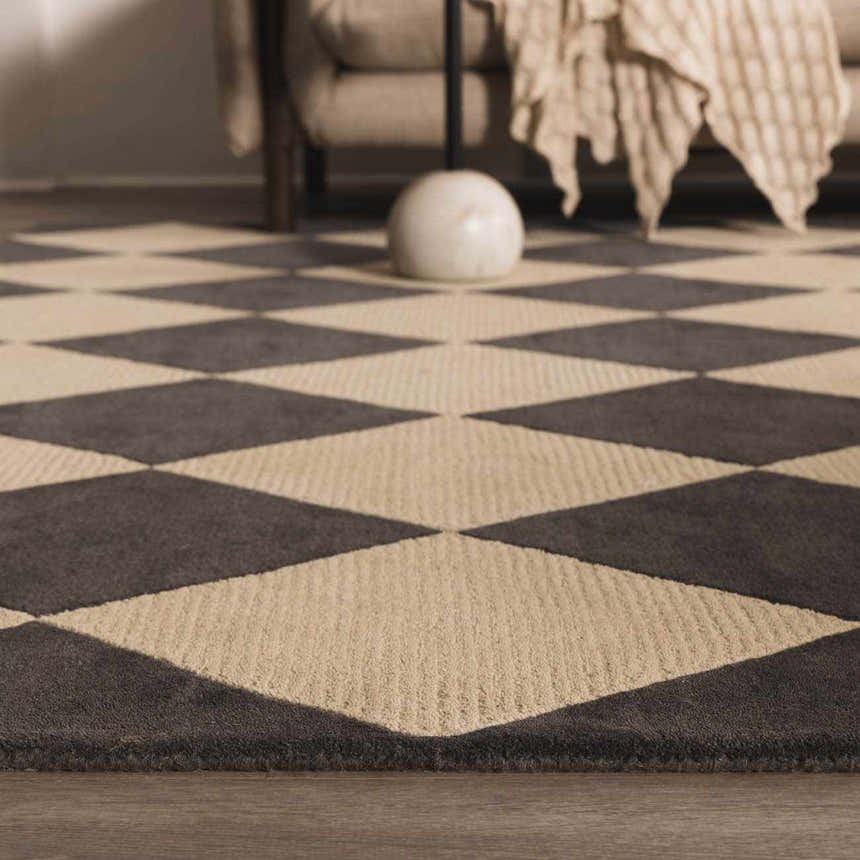 Close-up of the Aradia Charcoal Area Rug. Hand-tufted wool rug with a bold charcoal and beige diamond pattern. Styleshot